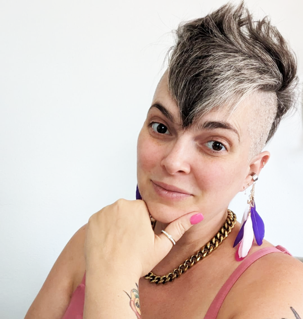 head and shoulder portrait of short heaired Melissa wearing a strappy top and feather earings